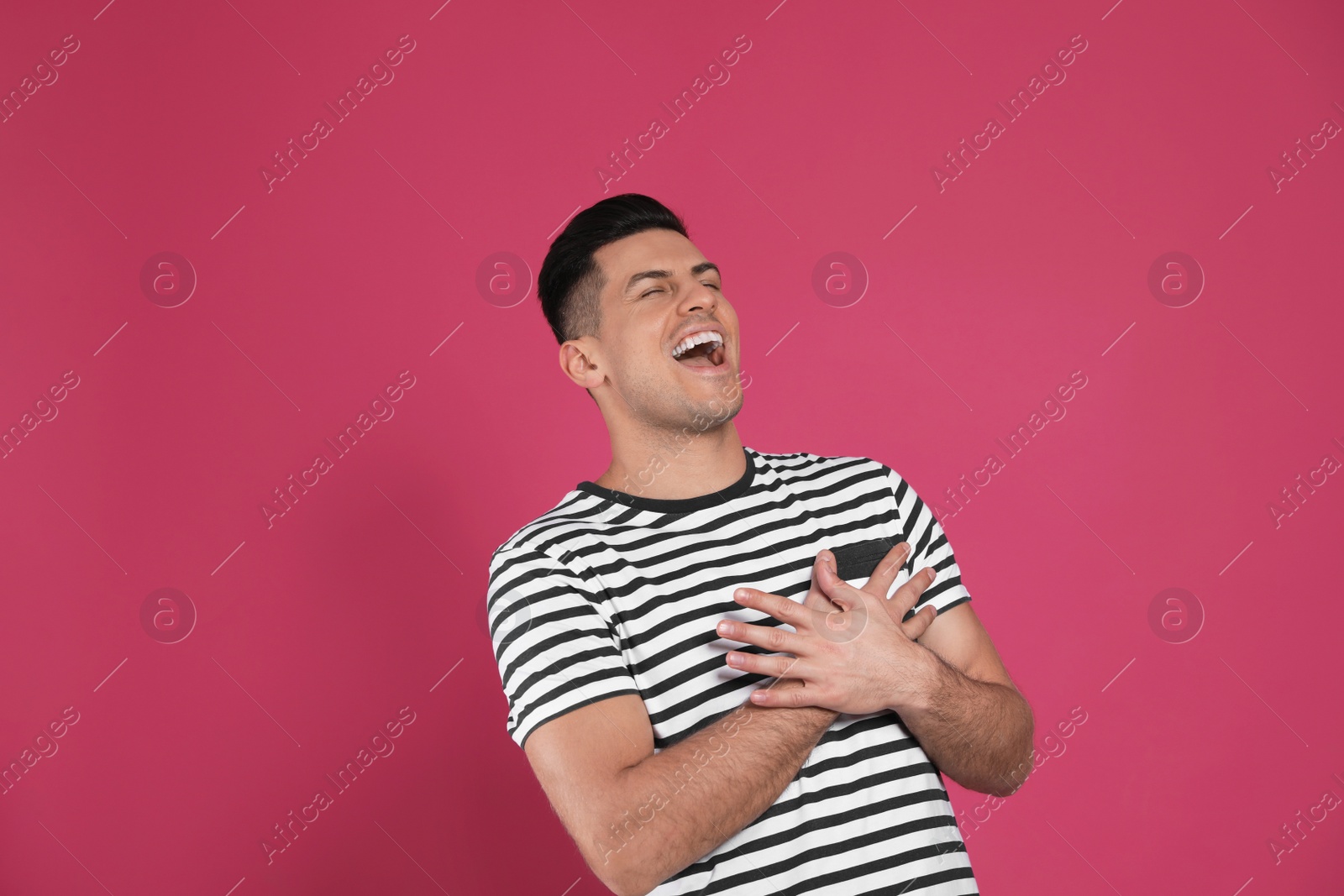 Photo of Handsome man laughing on maroon background. Funny joke