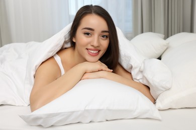 Beautiful young woman lying in bed at home