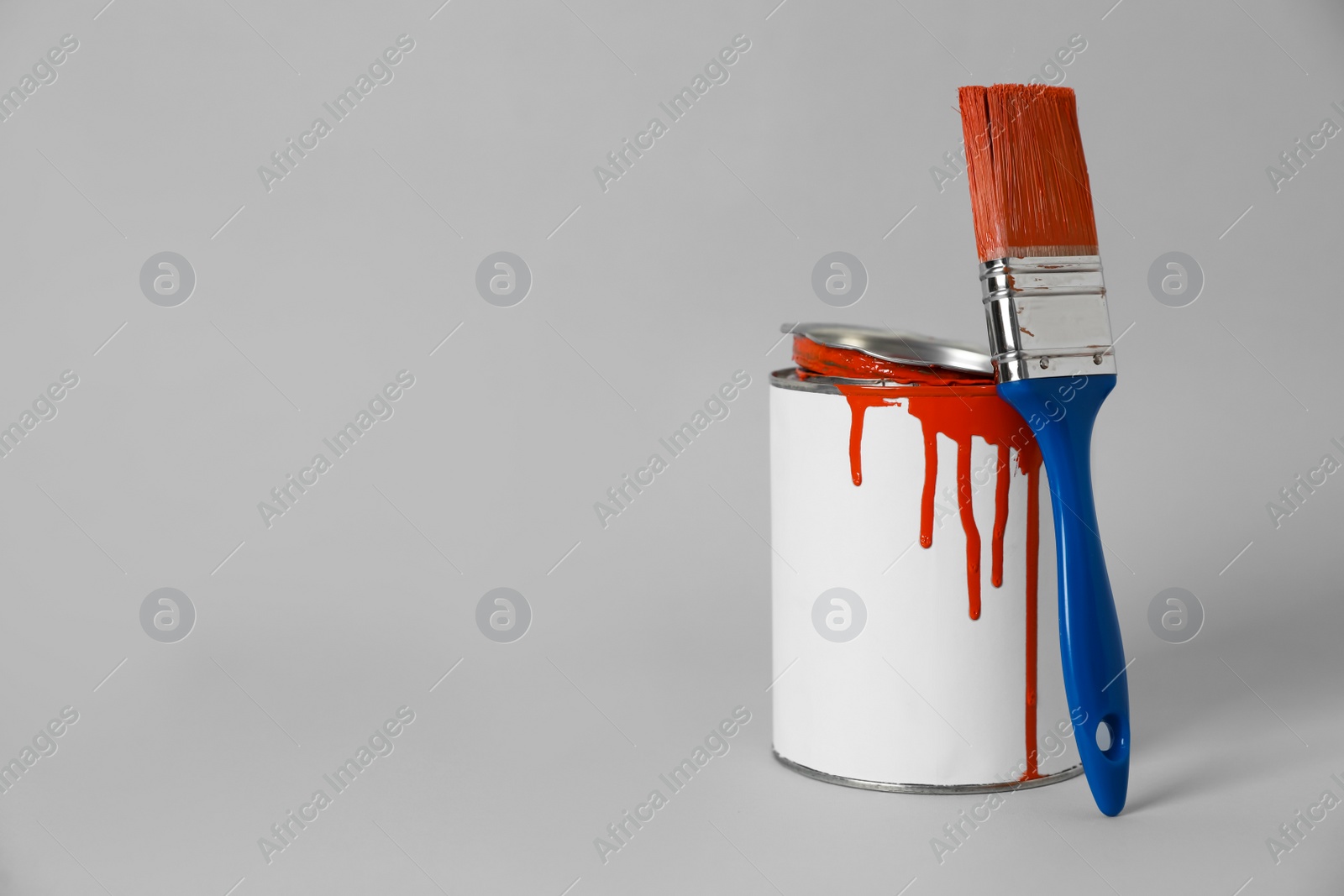 Photo of Can of orange paint and brush on grey background. Space for text