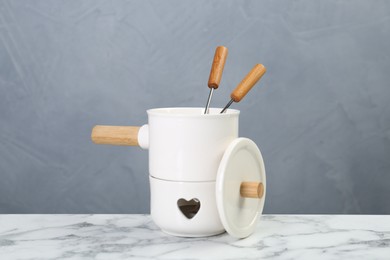 Fondue set on white marble table against light grey background