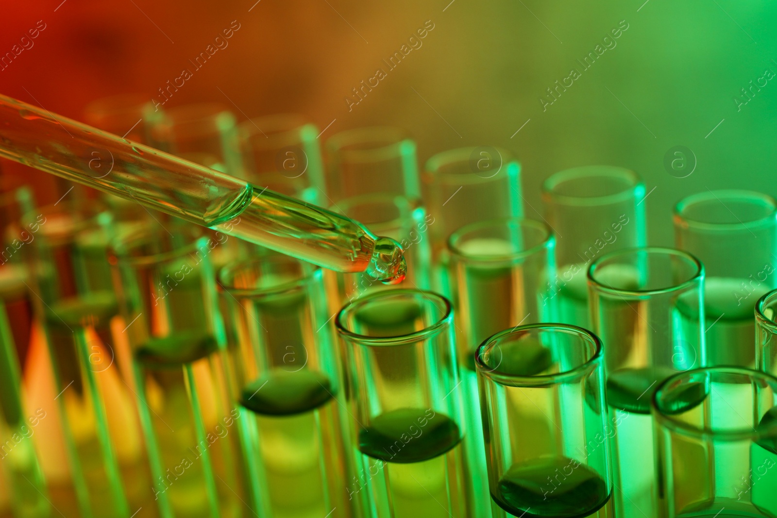 Photo of Dropping sample into test tube with liquid, closeup. Color tone effect