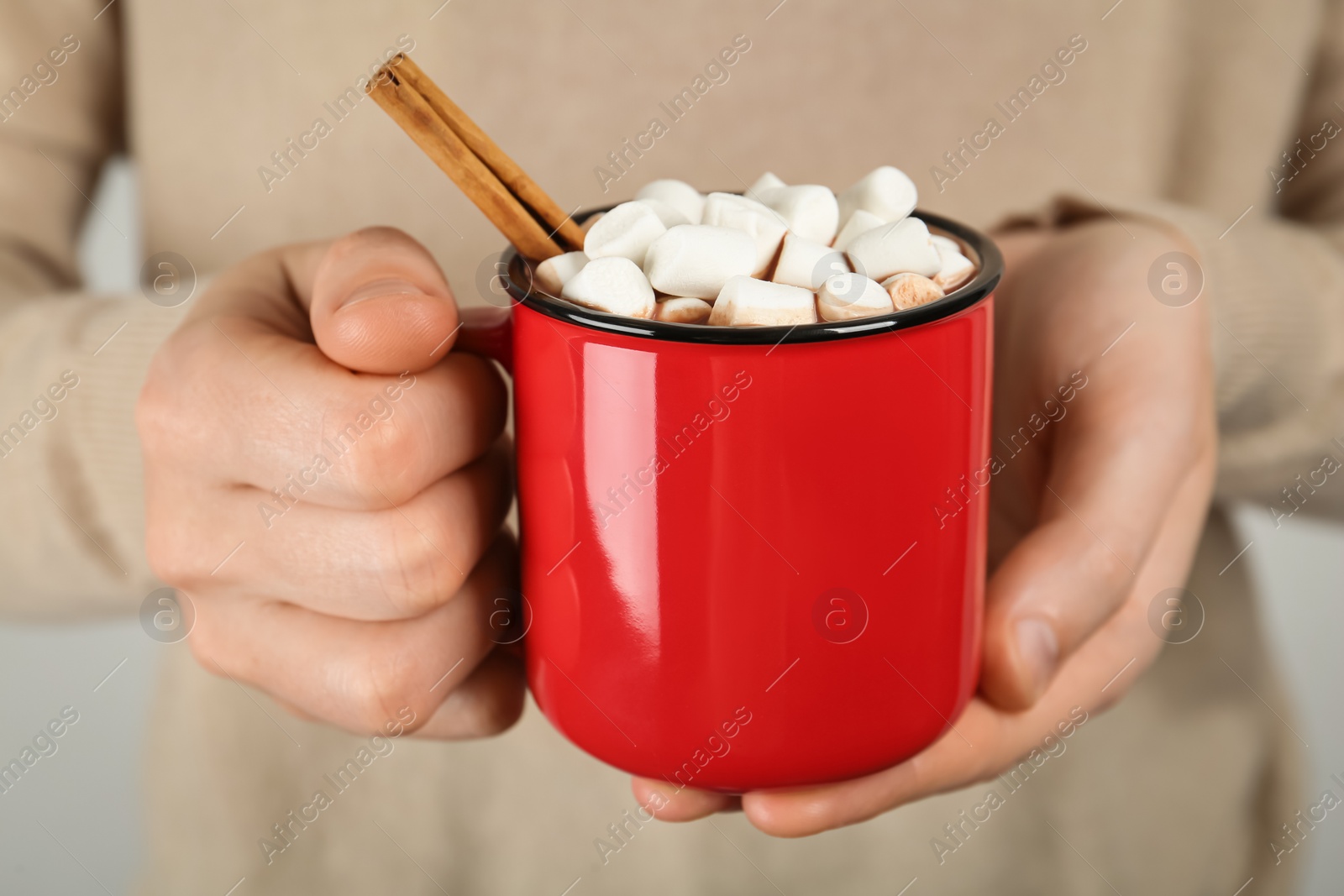 Photo of Woman holding cup of delicious hot chocolate with marshmallows and cinnamon stick, closeup