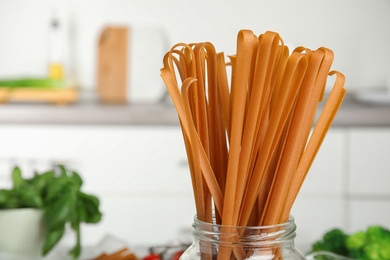 Uncooked buckwheat noodles on blurred background, closeup