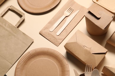 Photo of Eco friendly food packaging. Paper containers and tableware on beige background