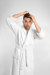 Young man in bathrobe on white background