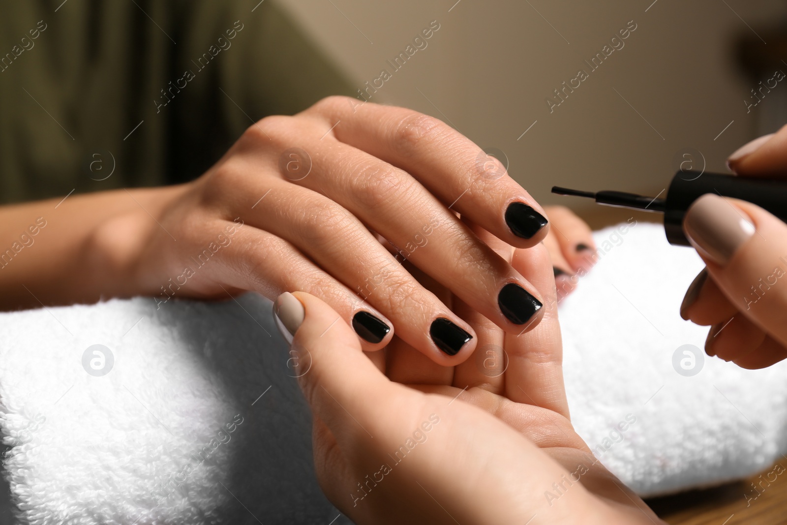 Photo of Manicurist painting client's nails with polish in salon, closeup