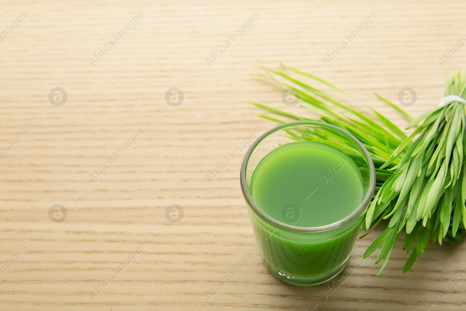 Shot glass of wheat grass juice and sprouts on wooden table, space for text Photo of Shot glass of wheat grass juice and sprouts on wooden table, space for text