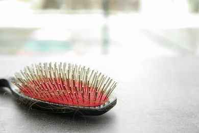 Photo of Brush with lost hair on table. Alopecia problem