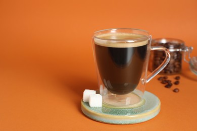 Photo of Coaster with cup of coffee on orange background, space for text