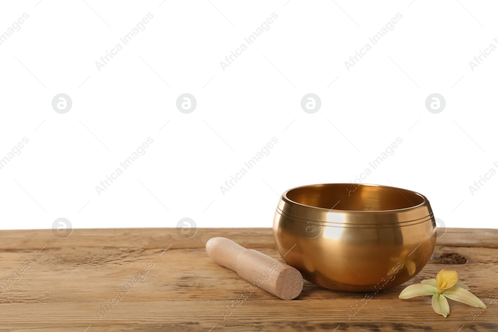 Photo of Golden singing bowl, mallet and flower on wooden table against white background, space for text