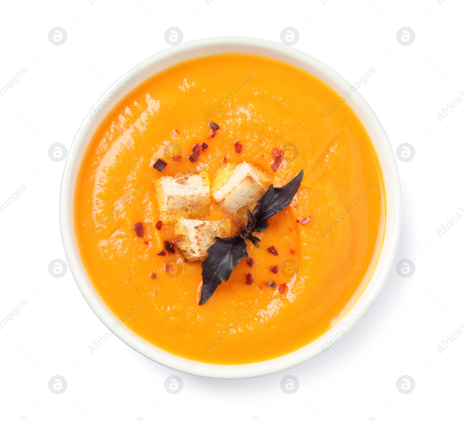 Image of Tasty creamy pumpkin soup in bowl on white background, top view