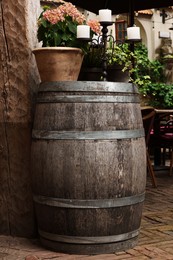 Photo of Traditional wooden barrel, beautiful houseplant and candlestick outdoors