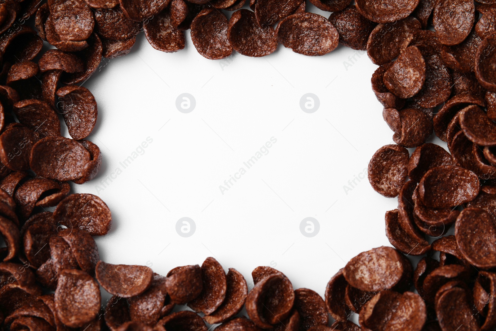 Photo of Breakfast cereal. Frame made of chocolate corn flakes on white background, top view. Space for text