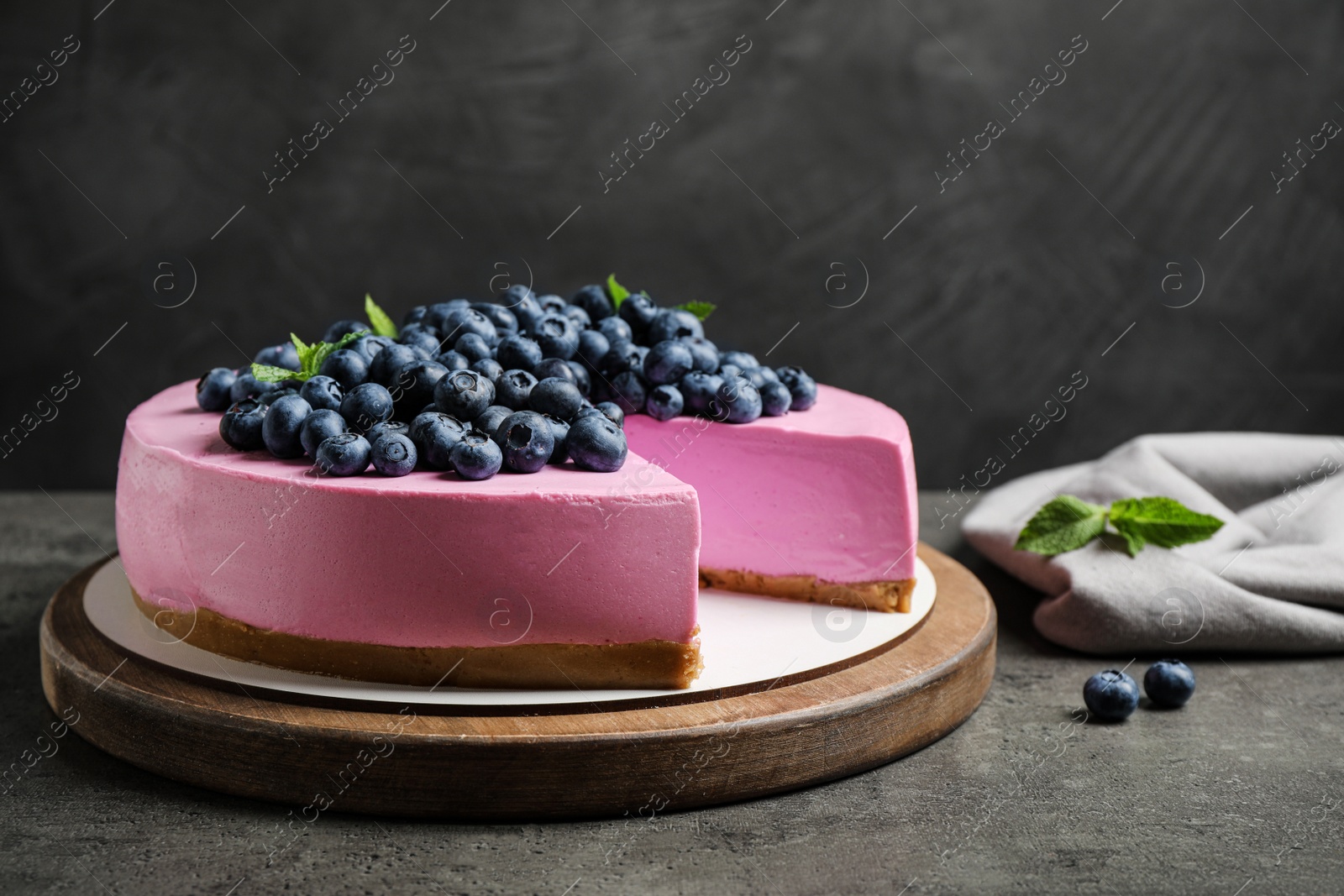 Photo of Board with tasty blueberry cake on grey table. Space for text