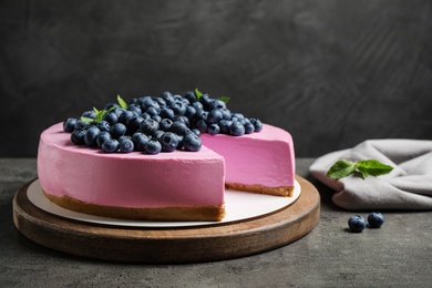 Board with tasty blueberry cake on grey table. Space for text