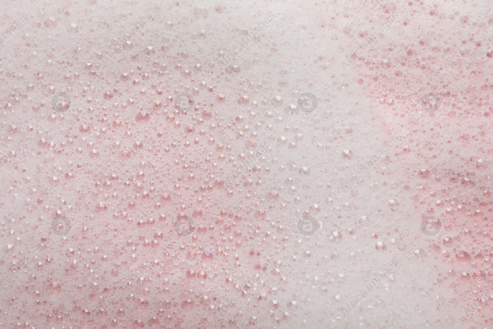 Photo of Fluffy soap foam on pink background, closeup