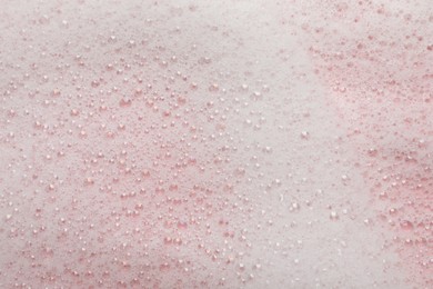 Photo of Fluffy soap foam on pink background, closeup