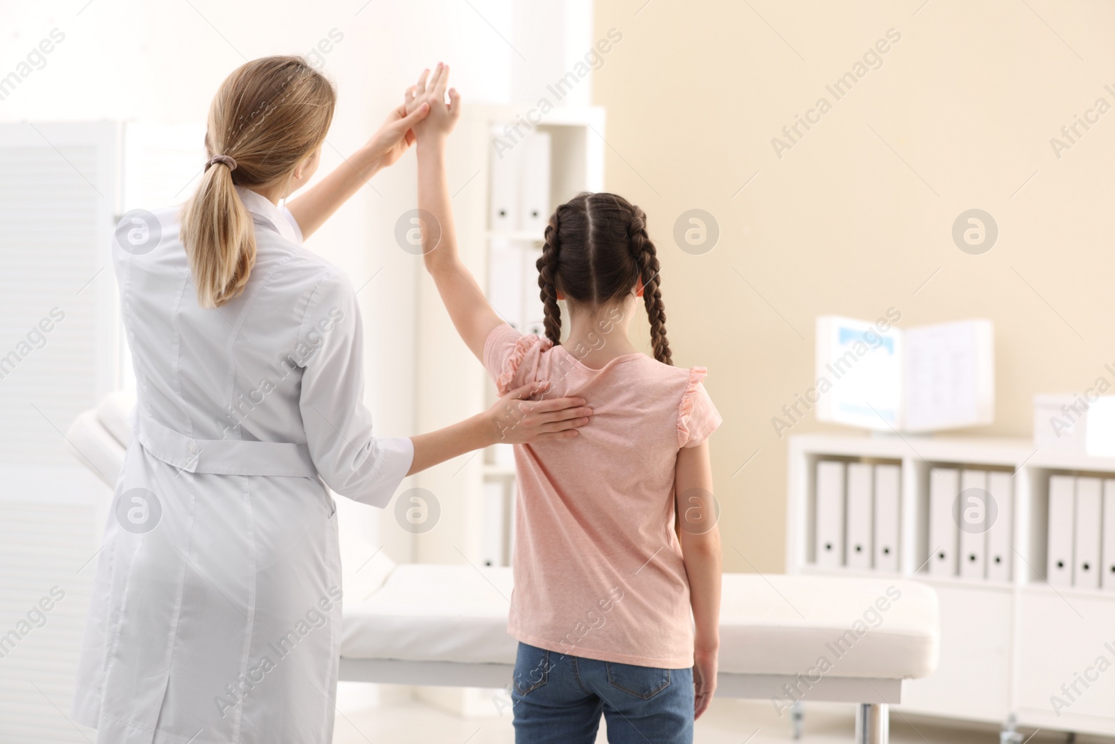 Photo of Chiropractor examining child with back pain in clinic