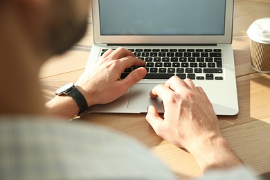 Photo of Freelancer working on laptop at table indoors, closeup