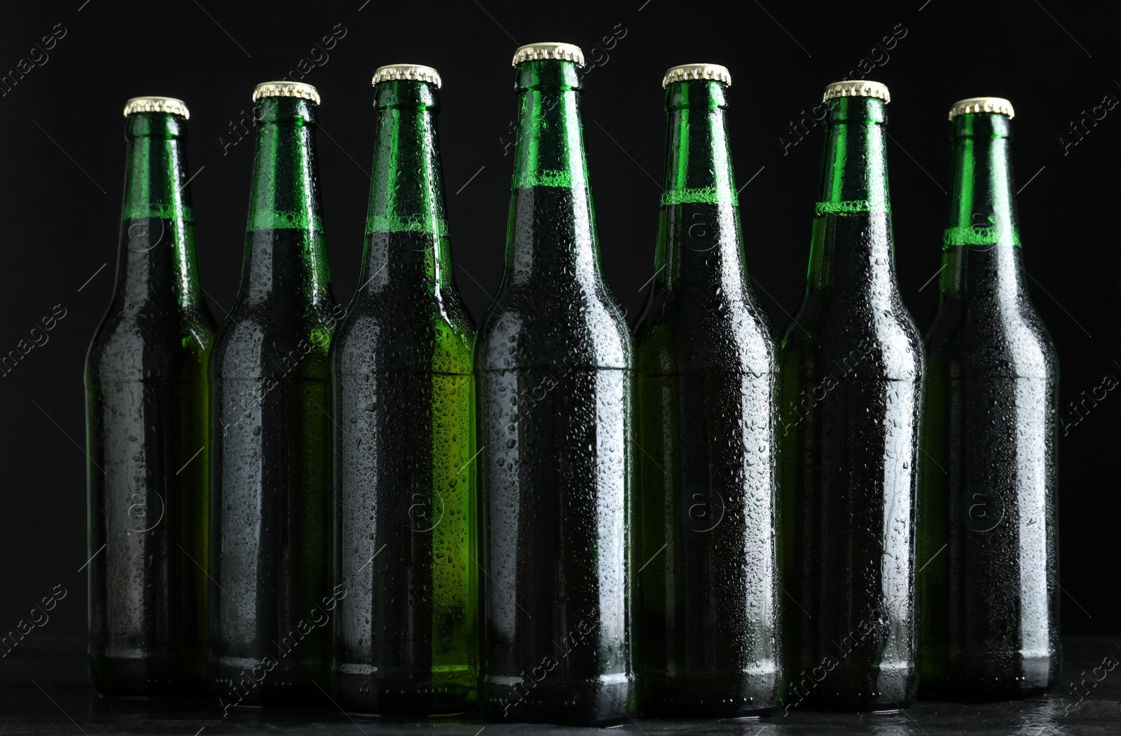 Photo of Glass bottles of beer on table against black background