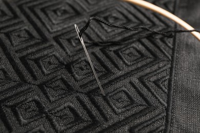 Photo of Needle with thread in black shirt, closeup. Ukrainian national clothes