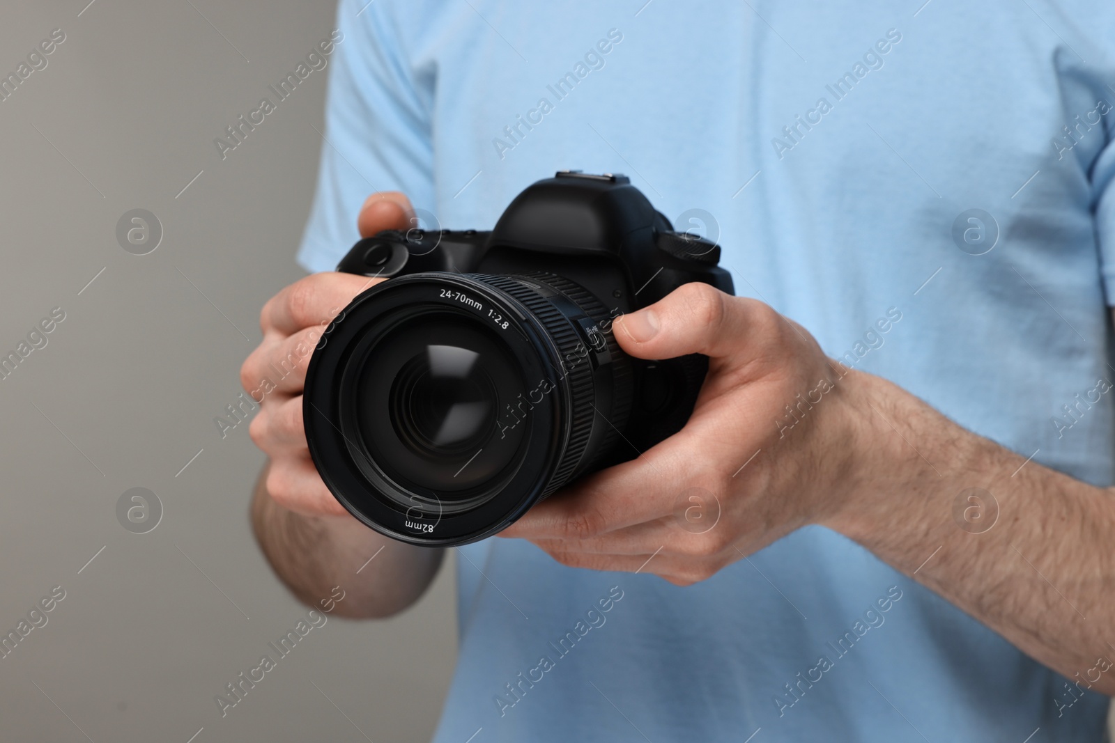 Photo of Photographer holding camera on grey background, closeup