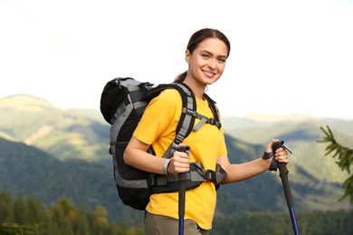 Photo of Woman with backpack and trekking poles hiking in mountains