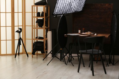Photo of Professional equipment and composition with tasty meat medallions on wooden table in studio. Food photography