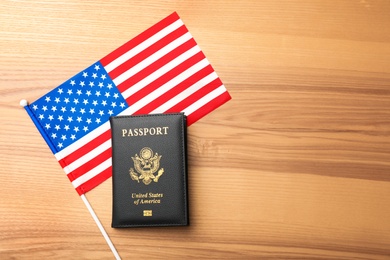 Flat lay composition with flag of USA and passport on wooden background. Space for text