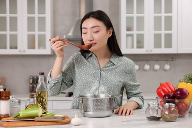 Photo of Beautiful woman tasting food after cooking in kitchen