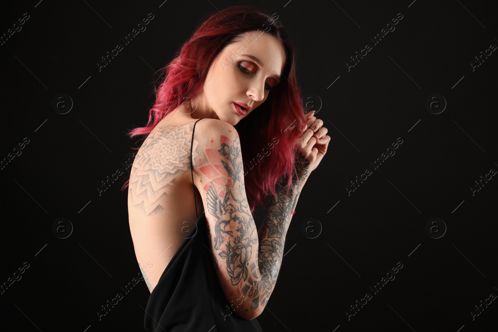 Photo of Beautiful woman with tattoos on body against black background