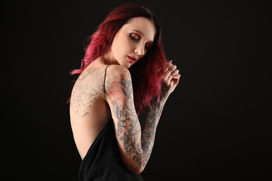 Photo of Beautiful woman with tattoos on body against black background