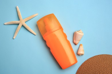 Bottle of sunscreen, starfish and seashells on light blue background, flat lay