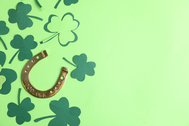 Flat lay composition with clover leaves and horseshoe on green background, space for text. St. Patrick's day
