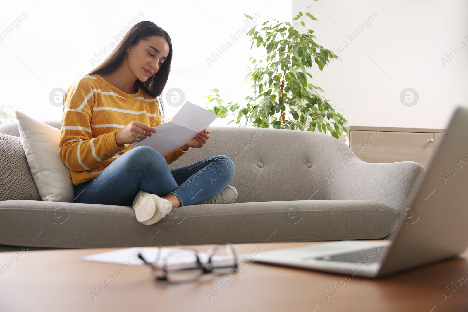 Photo of Woman reading letter on sofa at home