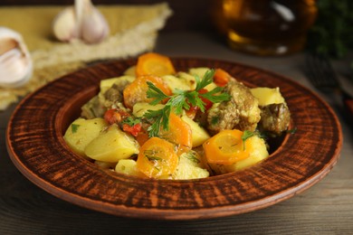 Tasty cooked dish with potatoes in earthenware on wooden table, closeup