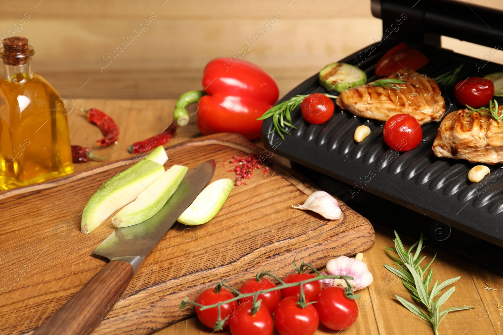 Photo of Electric grill with different products and knife on wooden table