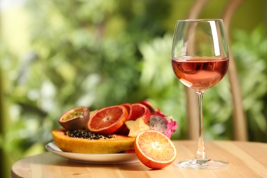 Photo of Delicious exotic fruits and wine on wooden table