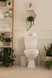 Photo of Restroom interior with white toilet and green houseplants