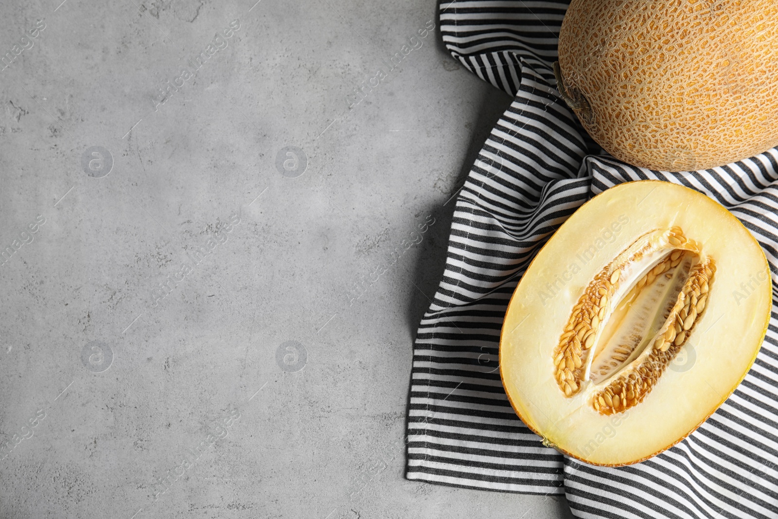 Photo of Tasty ripe melons on grey table, flat lay. Space for text