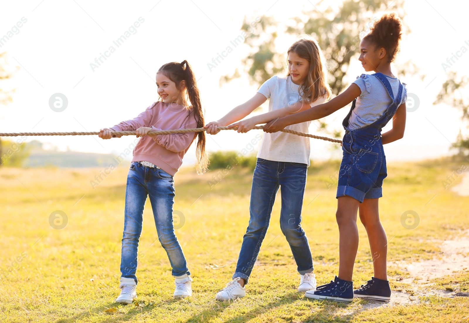 Photo of Cute little children playing with rope outdoors on sunny day