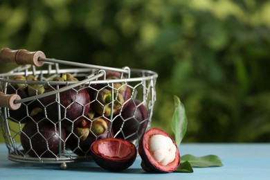 Photo of Delicious tropical mangosteen fruits on light blue table. Space for text