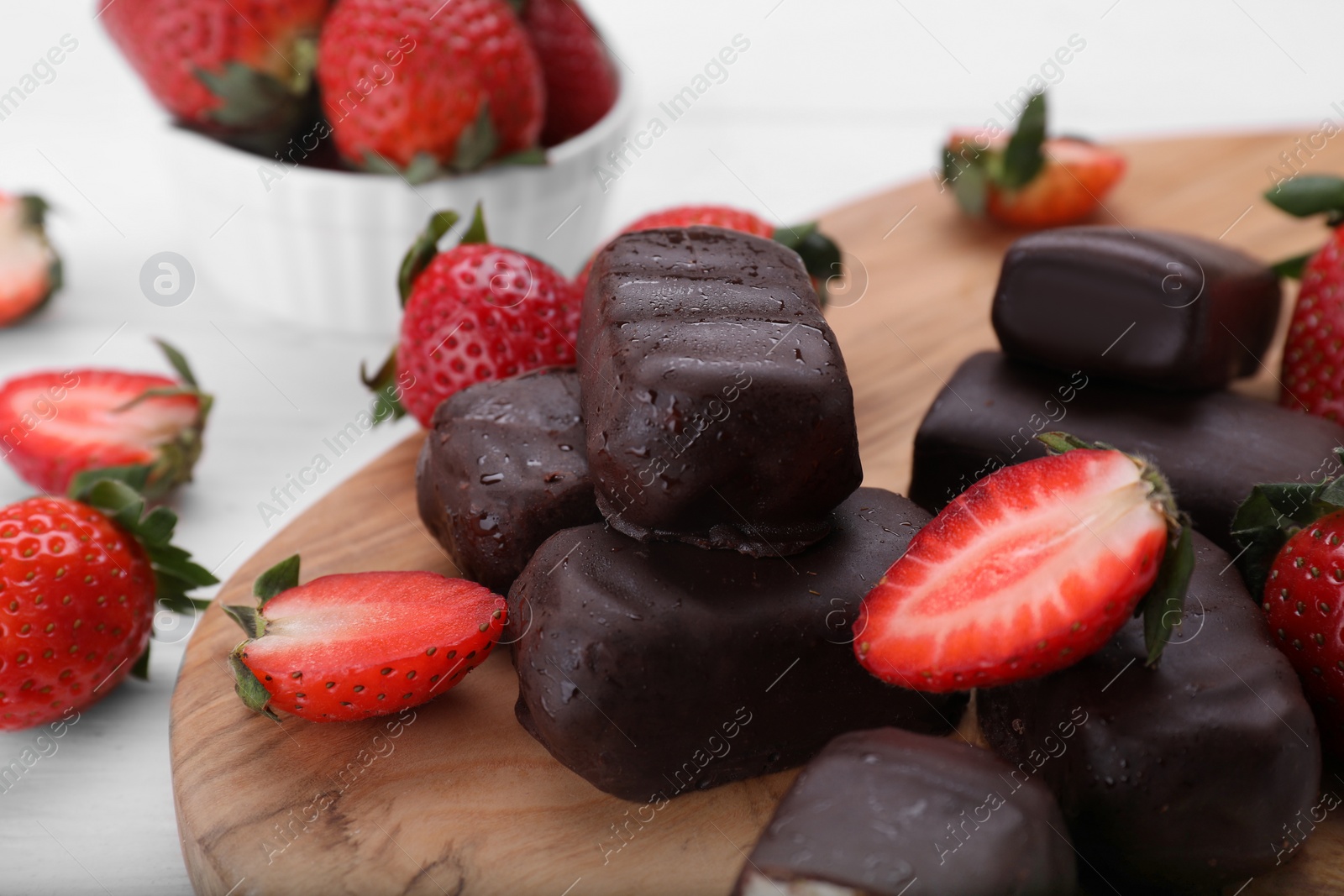 Photo of Delicious glazed curd snacks and fresh strawberries on white wooden table, closeup