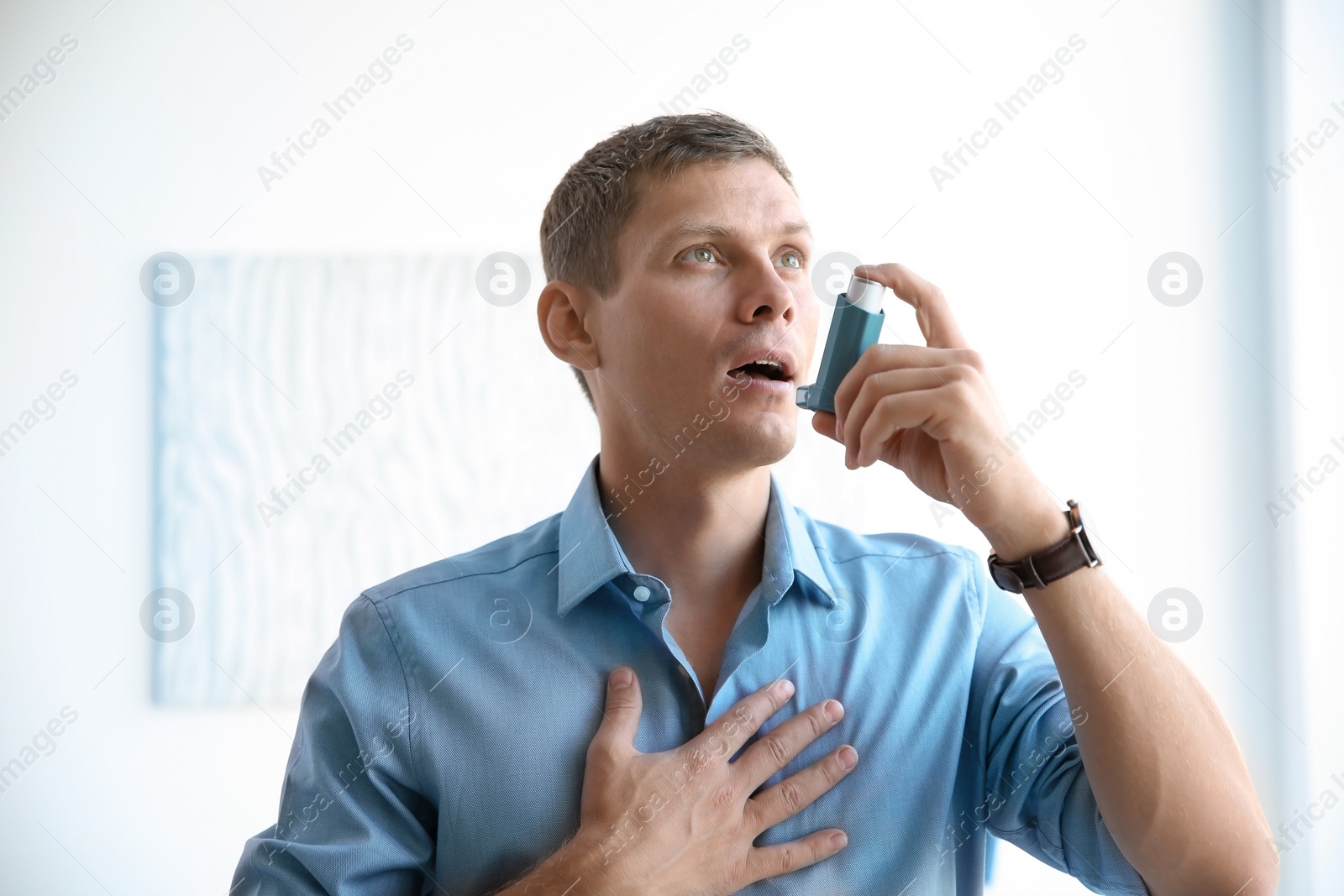 Photo of Young man using asthma inhaler at home