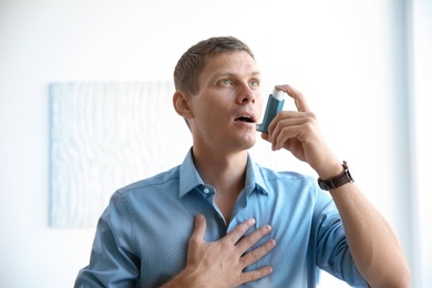 Young man using asthma inhaler at home