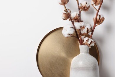 Photo of Cotton branches with fluffy flowers in vase on white background, closeup. Space for text