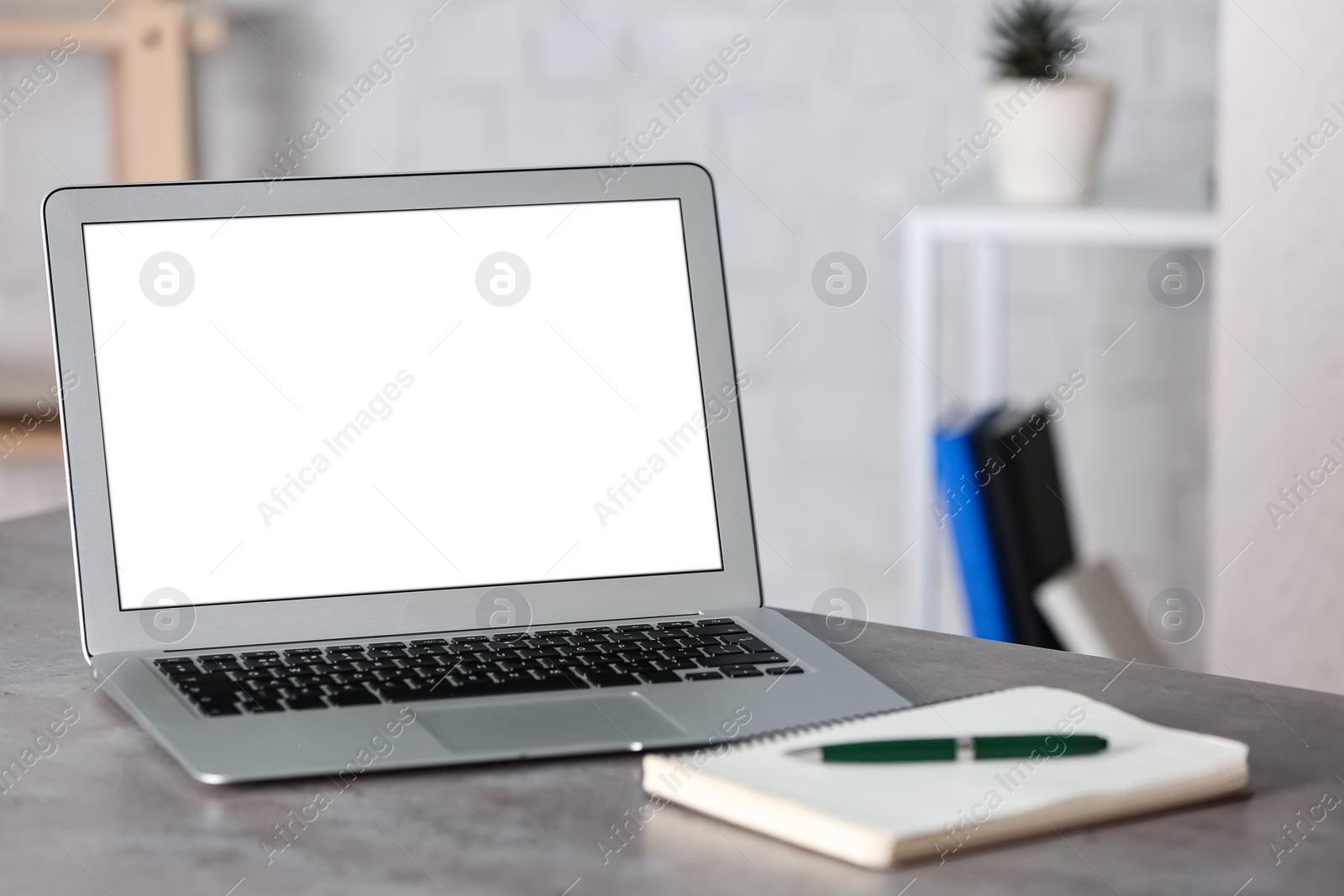 Photo of Modern laptop and notebook with pen on grey table in office. Space for text