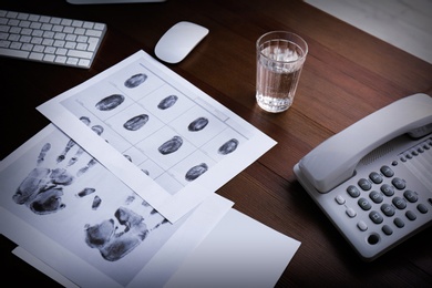 Photo of Fingerprints, corded phone and glass of water on table. Detective agency