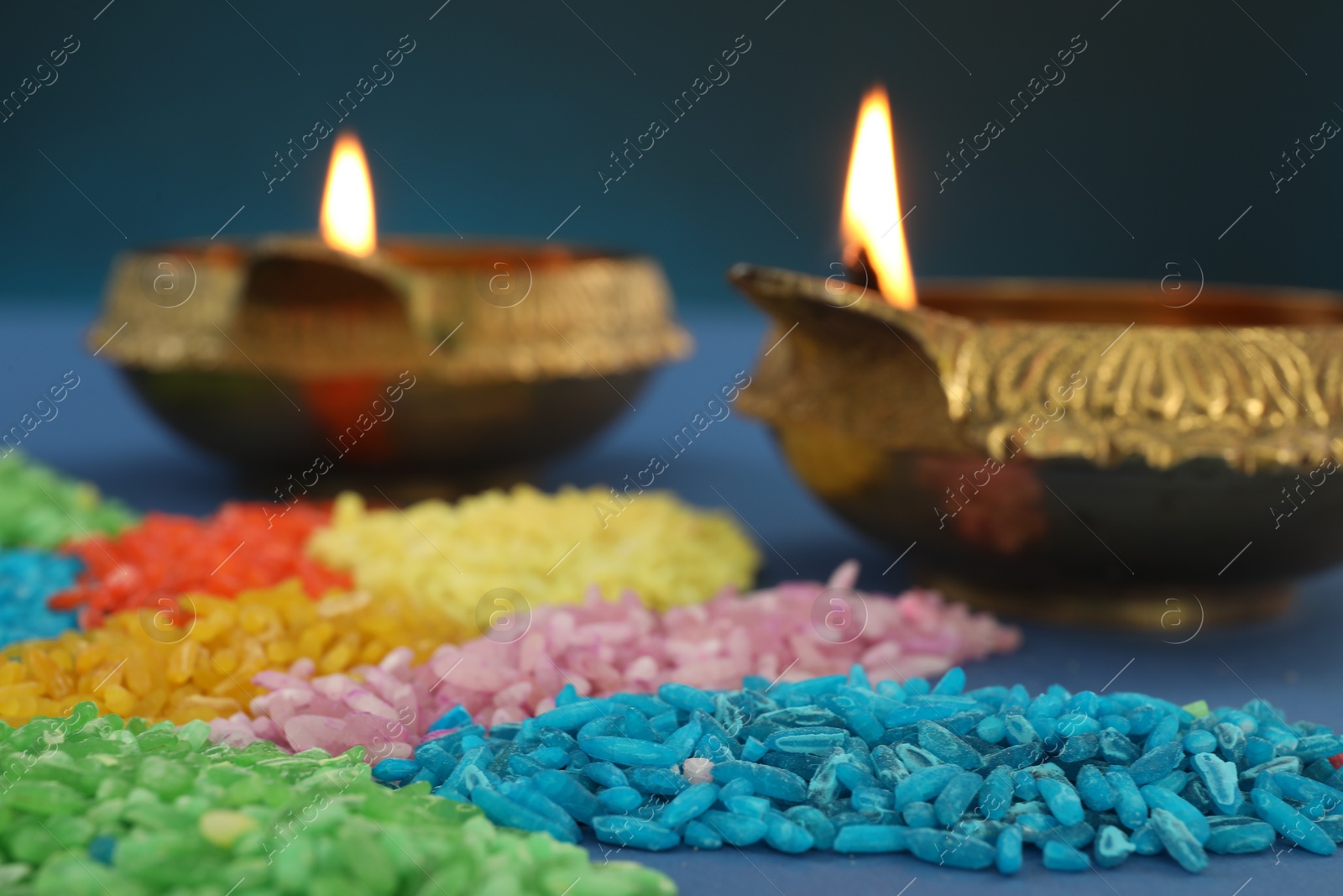 Photo of Diwali celebration. Diya lamps and colorful rangoli on blue background, closeup