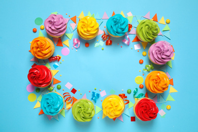 Photo of Colorful birthday cupcakes on light blue background, flat lay. Space for text